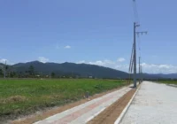 Terreno plano com rua asfaltada e montanhas ao fundo